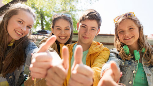 four satisfied young people show thumbs up